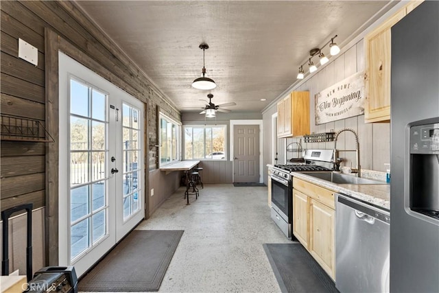 kitchen with a sink, light brown cabinetry, light countertops, stainless steel appliances, and decorative light fixtures