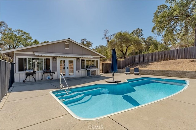 view of pool featuring french doors, a patio, area for grilling, and a fenced backyard