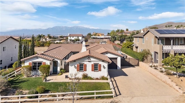 mediterranean / spanish-style house with a tiled roof, fence private yard, a mountain view, and driveway