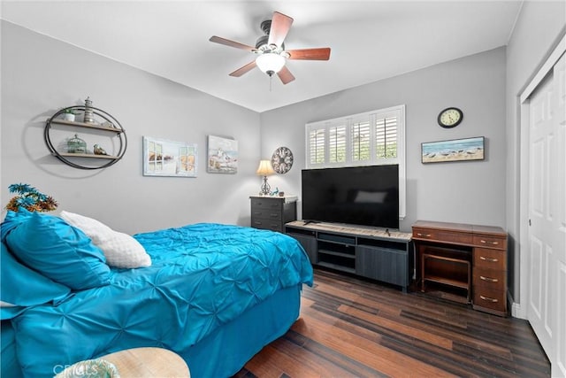 bedroom with a closet, dark wood-type flooring, and a ceiling fan