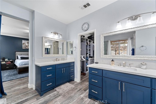 full bath featuring visible vents, wood finished floors, two vanities, and a sink