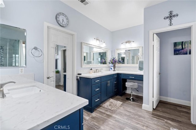 bathroom with visible vents, a shower with door, wood finished floors, baseboards, and vanity