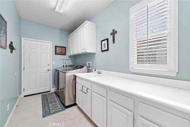 washroom featuring baseboards, light tile patterned floors, cabinet space, independent washer and dryer, and a sink