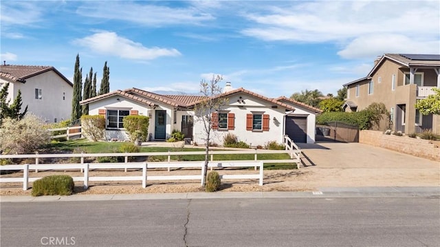 mediterranean / spanish-style home with a chimney, concrete driveway, a garage, a fenced front yard, and a tile roof