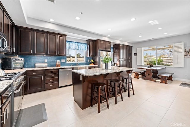 kitchen with a center island, a toaster, a kitchen breakfast bar, stainless steel appliances, and a sink