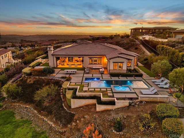 rear view of property featuring a tile roof, an outdoor pool, an outdoor living space with a fire pit, and a patio