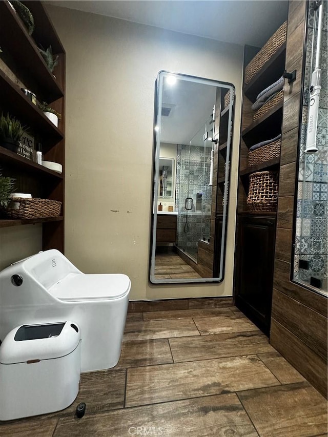 full bath featuring a shower stall, toilet, and wood finish floors