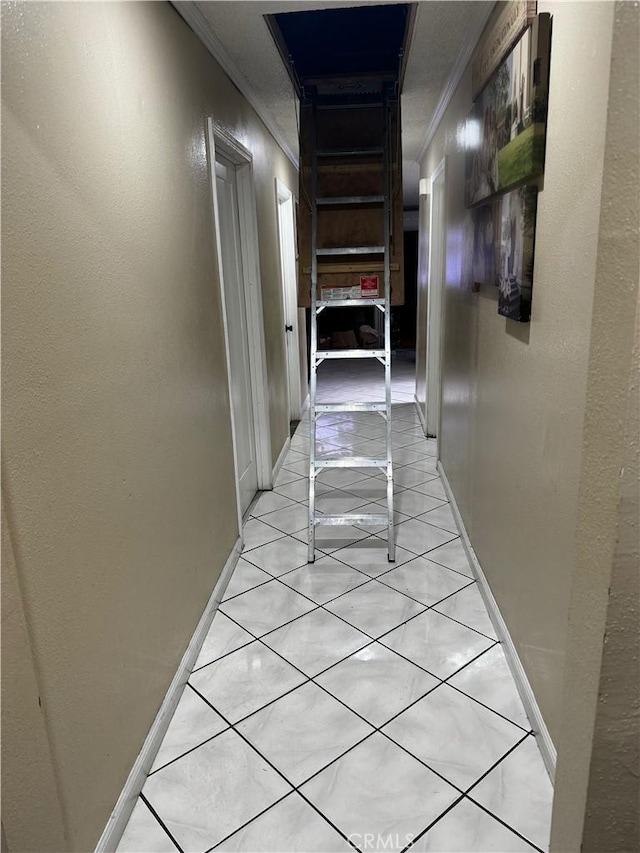 hallway featuring crown molding, light tile patterned floors, and baseboards