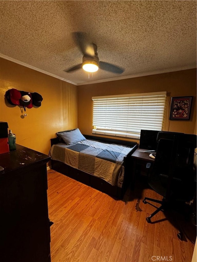 bedroom featuring a ceiling fan, a textured ceiling, wood finished floors, and crown molding