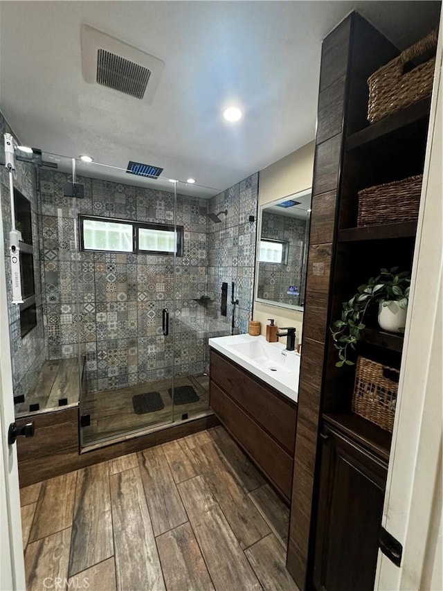 bathroom with vanity, a shower stall, wood finished floors, and visible vents