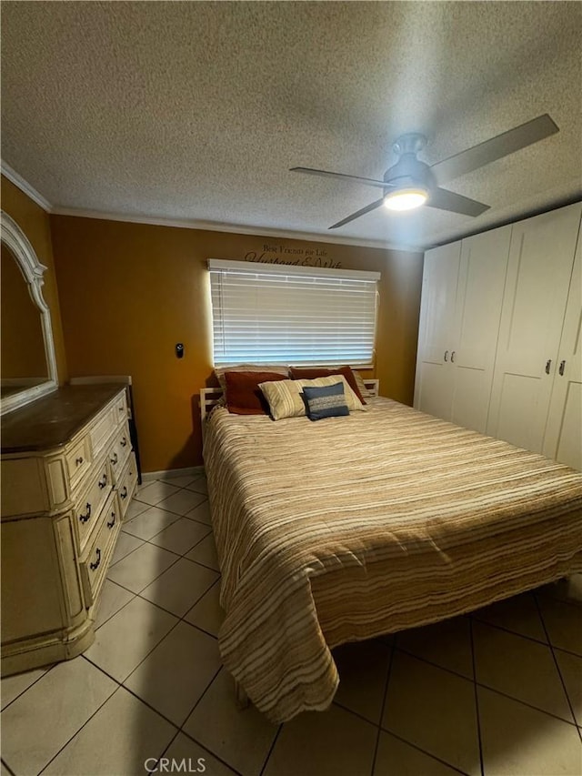 bedroom with light tile patterned floors, a closet, a textured ceiling, and a ceiling fan