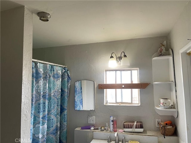 full bathroom with a sink, a shower with curtain, and a textured wall