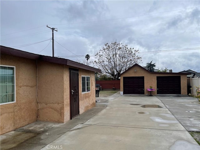 view of home's exterior featuring an outdoor structure, fence, a garage, and stucco siding