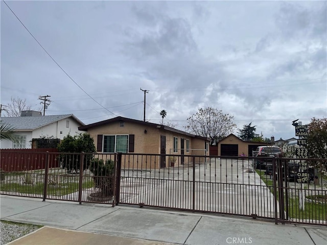 view of front facade with a fenced front yard, stucco siding, and a detached garage