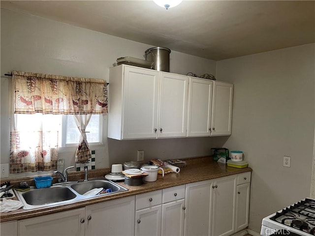 kitchen with a sink, white range with gas cooktop, and white cabinets