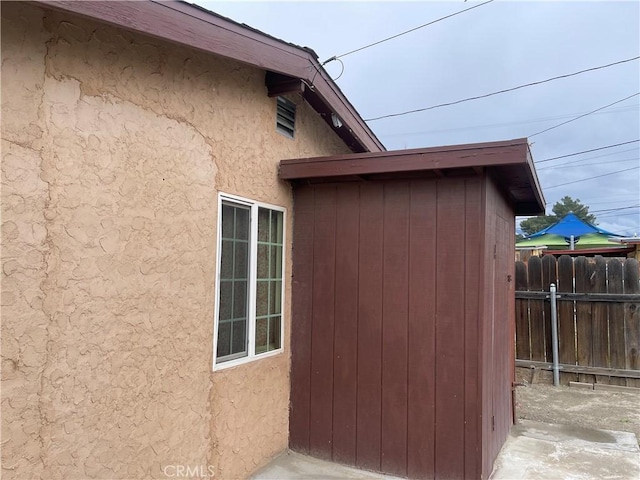 view of home's exterior with stucco siding and fence