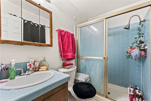 bathroom featuring vanity, a shower stall, and toilet