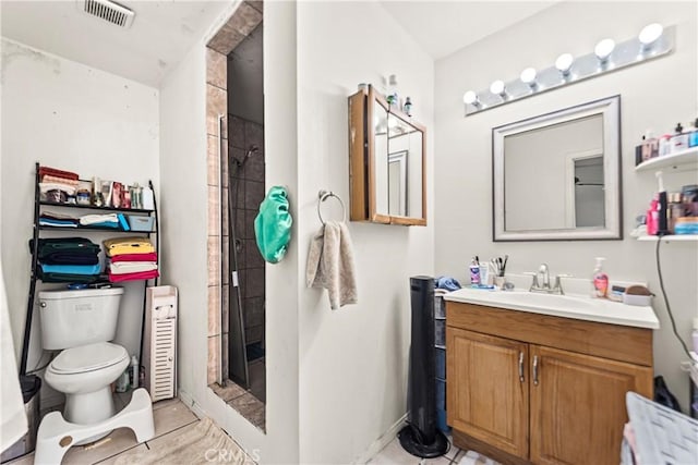 bathroom with visible vents, tiled shower, toilet, and vanity