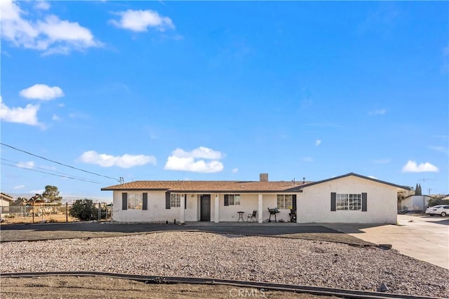 view of front of property with stucco siding, a chimney, and fence