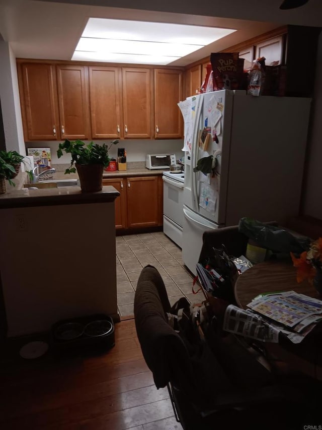 kitchen featuring brown cabinets, white appliances, light wood-style floors, and a sink