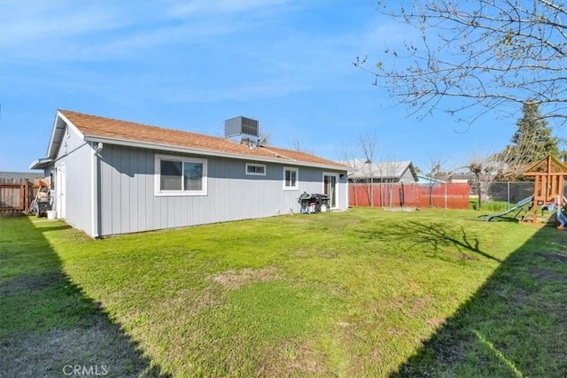 rear view of house featuring a playground, a yard, and fence