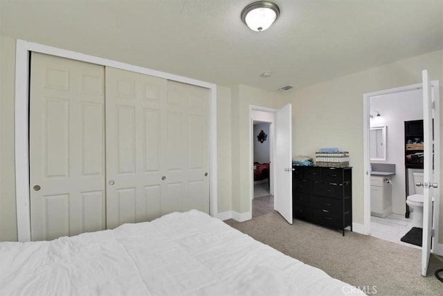 bedroom featuring visible vents, baseboards, carpet, a closet, and ensuite bath