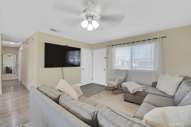 living room with a ceiling fan, wood finished floors, visible vents, and baseboards