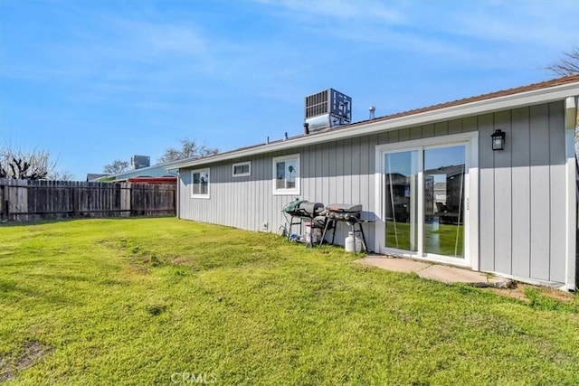 rear view of property with central air condition unit, a yard, and fence