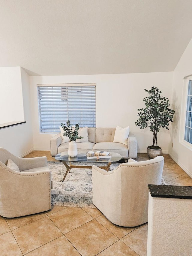 living room featuring light tile patterned flooring, baseboards, and lofted ceiling