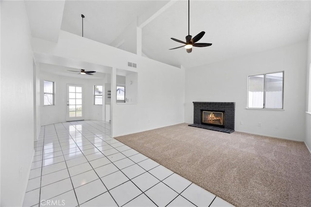 unfurnished living room with visible vents, ceiling fan, light carpet, a fireplace, and high vaulted ceiling