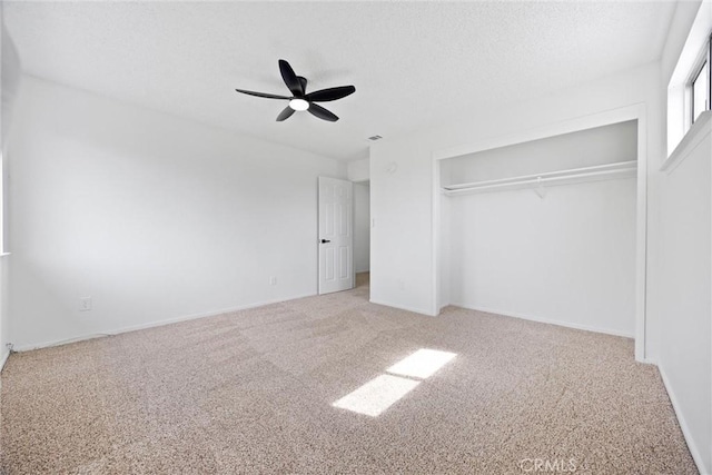 unfurnished bedroom with a textured ceiling, carpet floors, a closet, and a ceiling fan