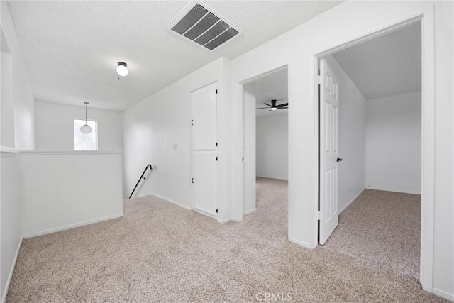 basement featuring baseboards, visible vents, carpet floors, and a textured ceiling