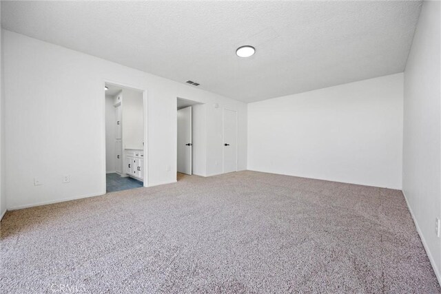 unfurnished bedroom with visible vents, carpet, a textured ceiling, and connected bathroom