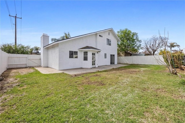 rear view of house featuring a gate, a fenced backyard, stucco siding, a patio, and a lawn
