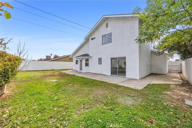 back of house with a fenced backyard, a yard, a patio area, and stucco siding