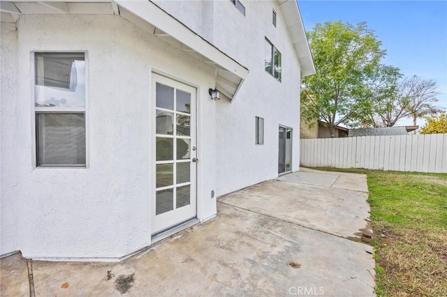 exterior space with fence, a patio area, and stucco siding