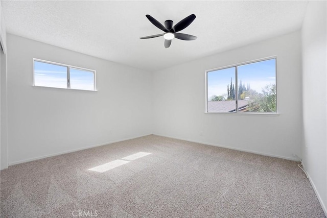 carpeted spare room featuring a ceiling fan and baseboards