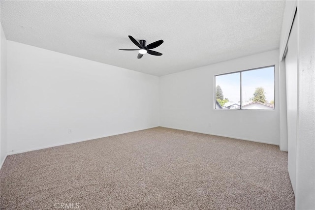 carpeted spare room with a textured ceiling and a ceiling fan