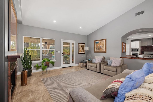 living room featuring visible vents, baseboards, vaulted ceiling, recessed lighting, and arched walkways