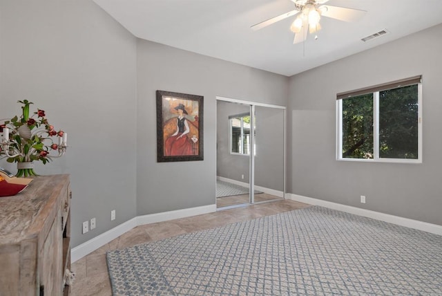 unfurnished room with light tile patterned floors, visible vents, a ceiling fan, and baseboards