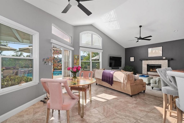 living area with a ceiling fan, baseboards, a high end fireplace, and high vaulted ceiling