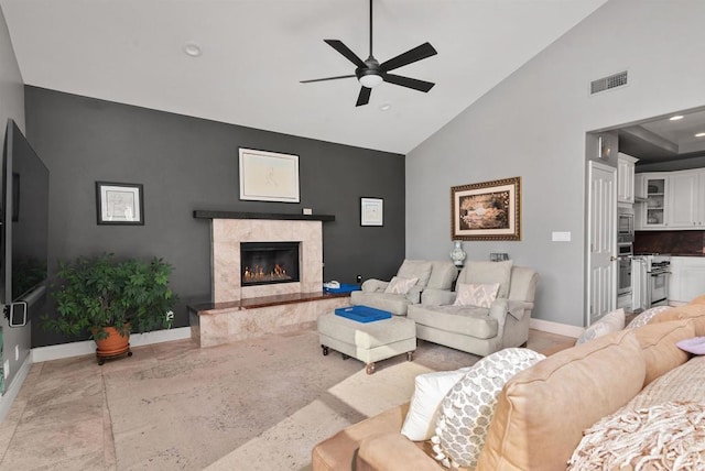 living room featuring visible vents, high vaulted ceiling, a high end fireplace, baseboards, and ceiling fan