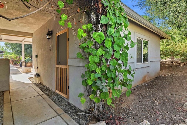 view of side of home featuring stucco siding and a patio area