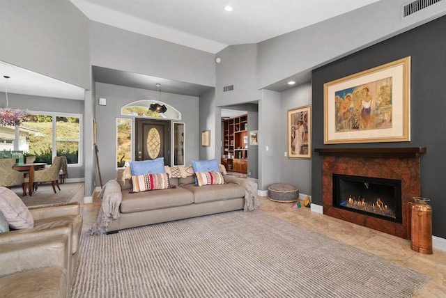 living area with visible vents, baseboards, and a glass covered fireplace