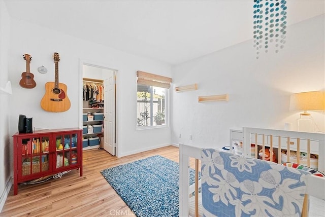 bedroom with a closet, baseboards, wood finished floors, and a spacious closet