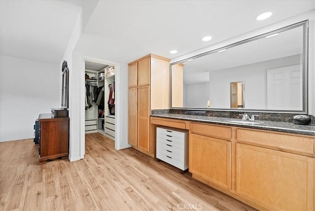 bathroom with recessed lighting, vanity, a walk in closet, and wood finished floors