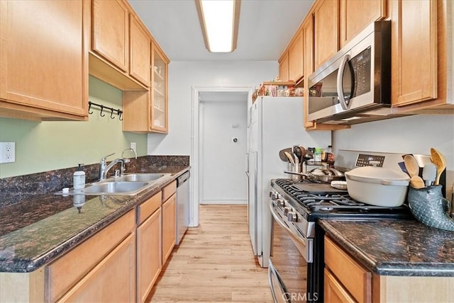 kitchen featuring dark stone countertops, appliances with stainless steel finishes, glass insert cabinets, and light wood-style floors