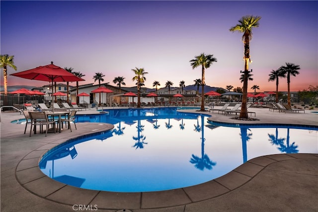 pool at dusk featuring a community pool and a patio area