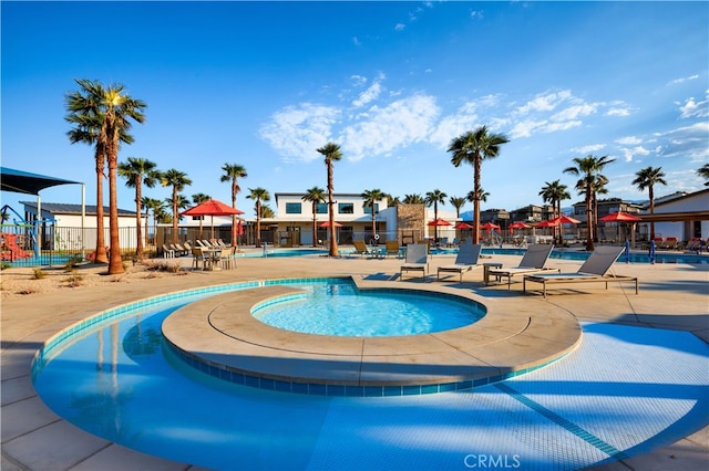 pool featuring a patio, fence, and a hot tub