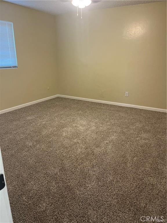 carpeted spare room with baseboards and a ceiling fan